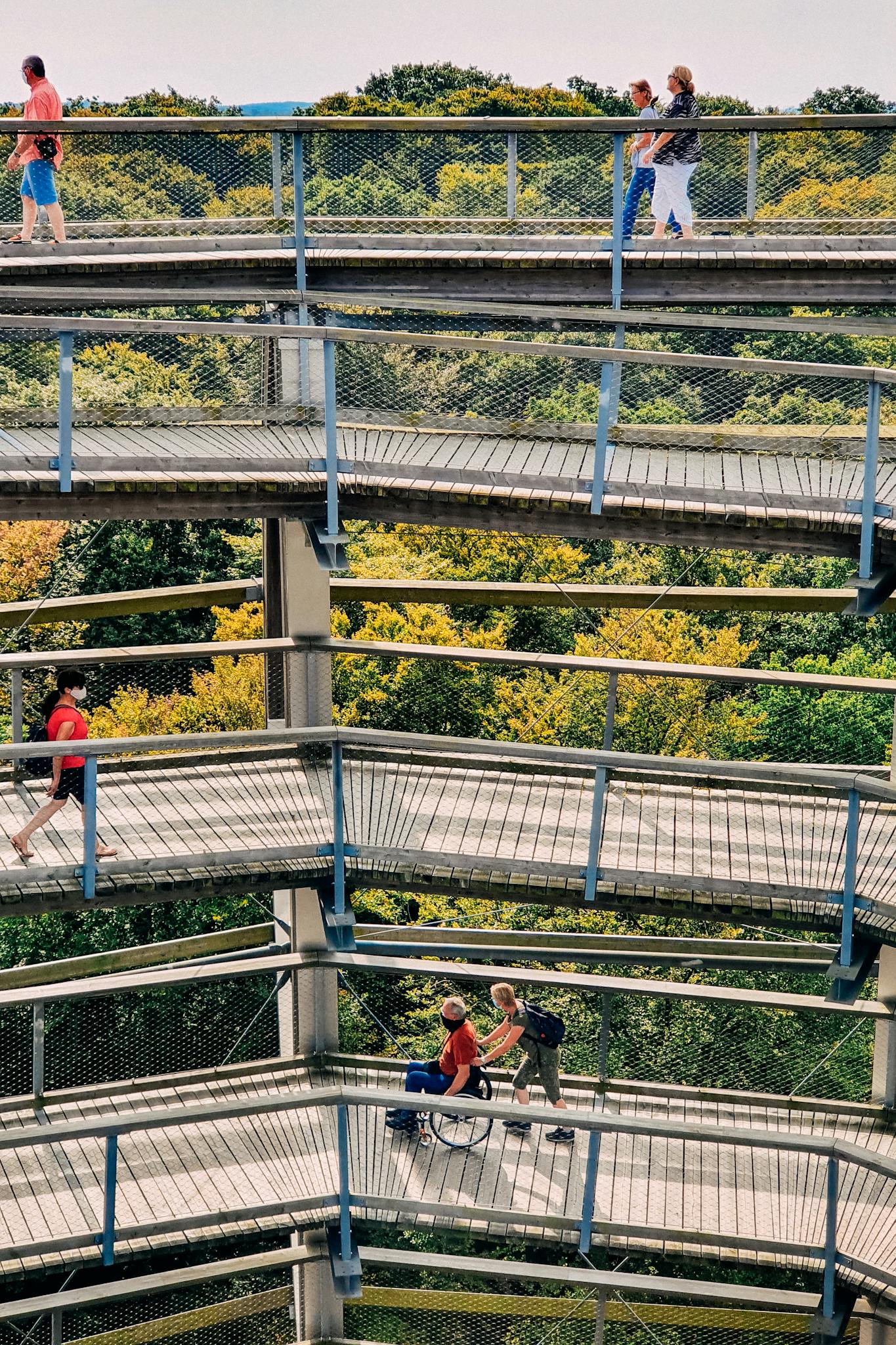 From above of unrecognizable group of tourists admiring greenery woods from old spiral observation tower